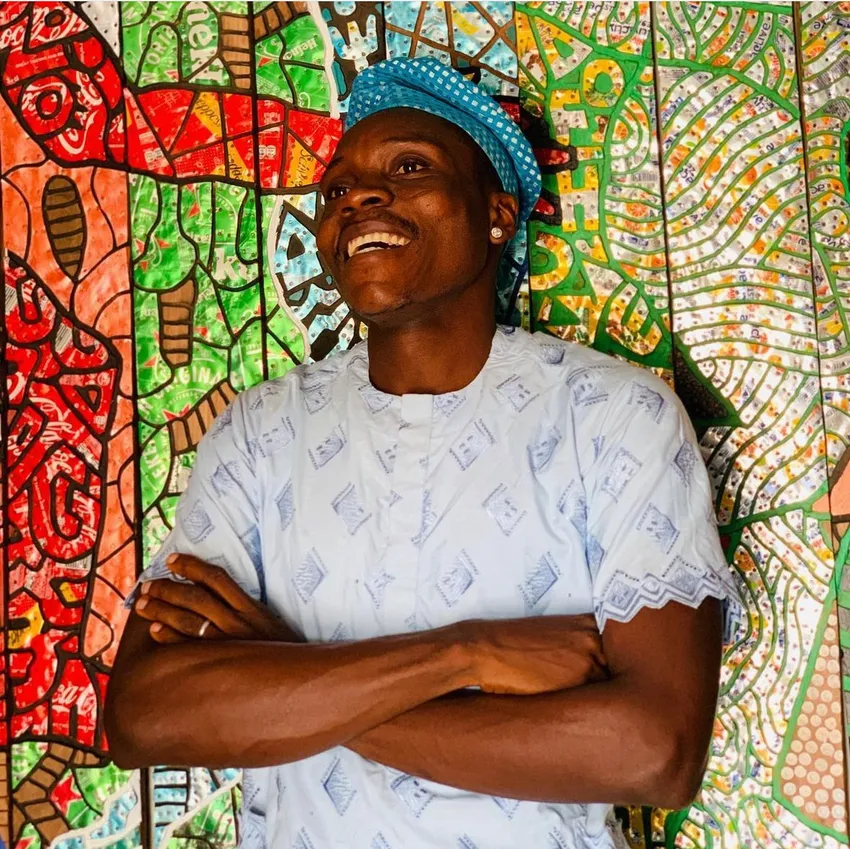 Man smiling in front of vibrant mural