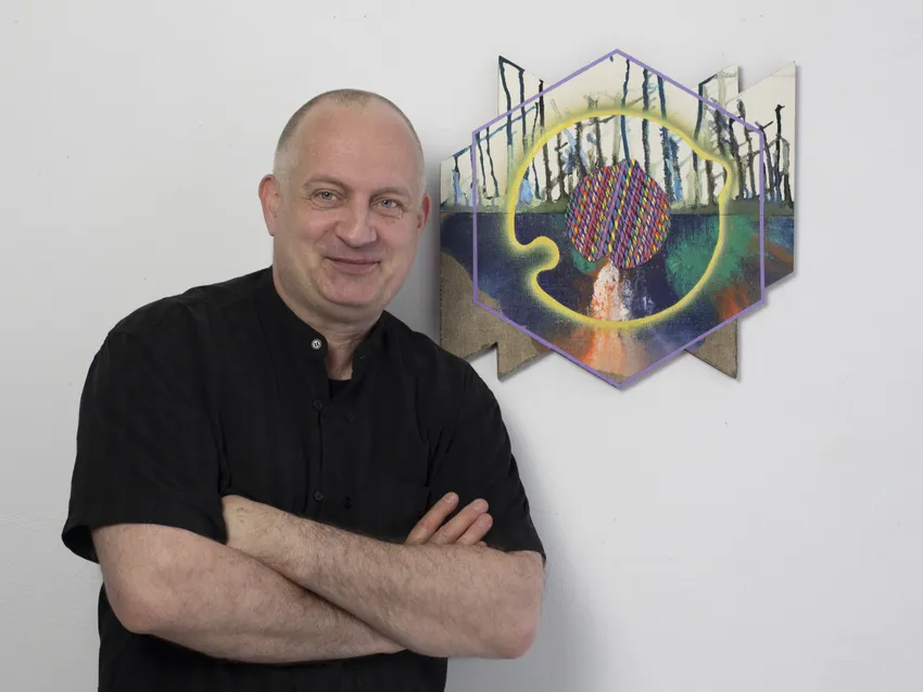 Artist posing with colorful geometric artwork