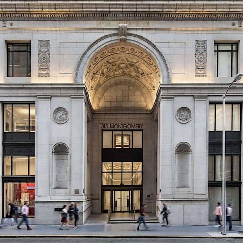 Pedestrians passing by grand arched entrance